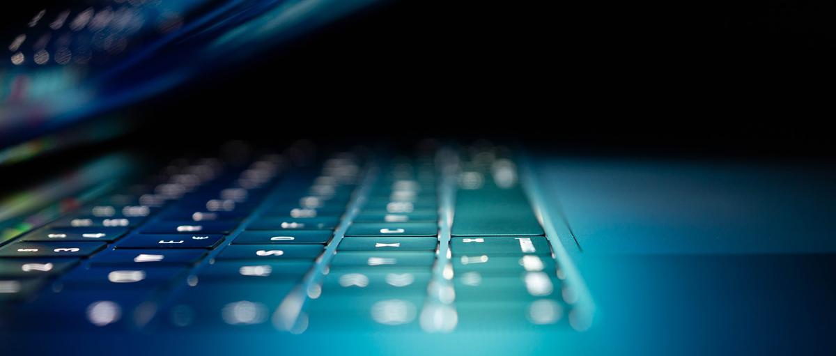 a close up side-view of a laptop that is partially open. the screen and keyboard glows. Photo credit phinehas adams xH3cUqeAUm0 via unsplash