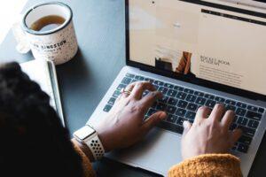 a shot from above a person working on an apple laptop. a Squarespace site is on their screen, and a mug of coffee sits to their left. Photo by Daniel Thomas on Unsplash